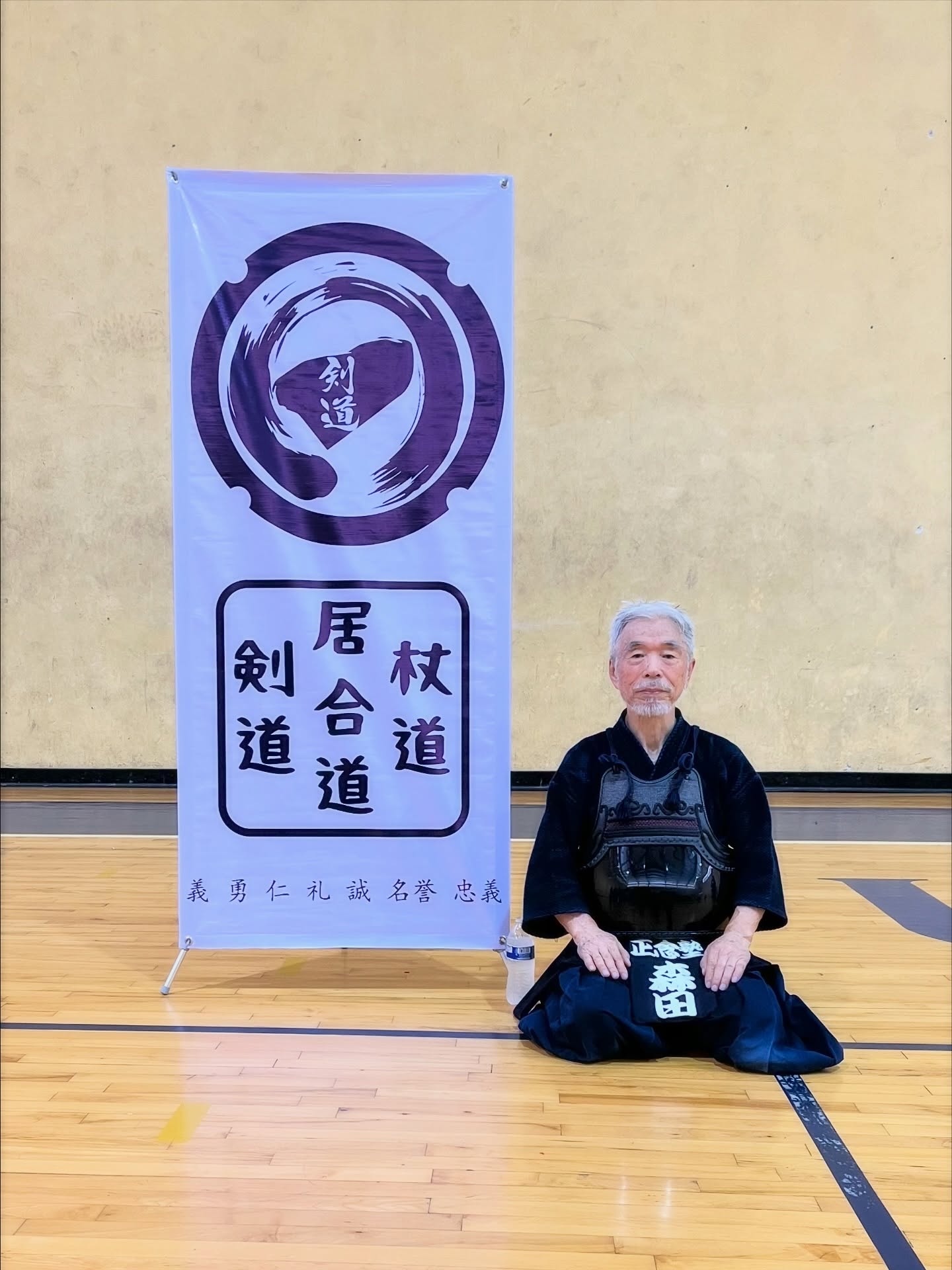 Sensei sentado junto al estandarte del dojo